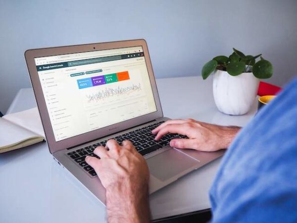 Startup guy typing on MacBook checting his Google search console for SEO ranking reports